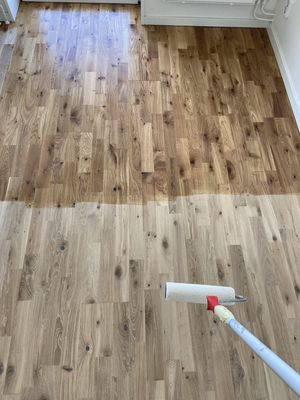 Lackning av ekgolv med roller, halva golvet färdigbehandlat
