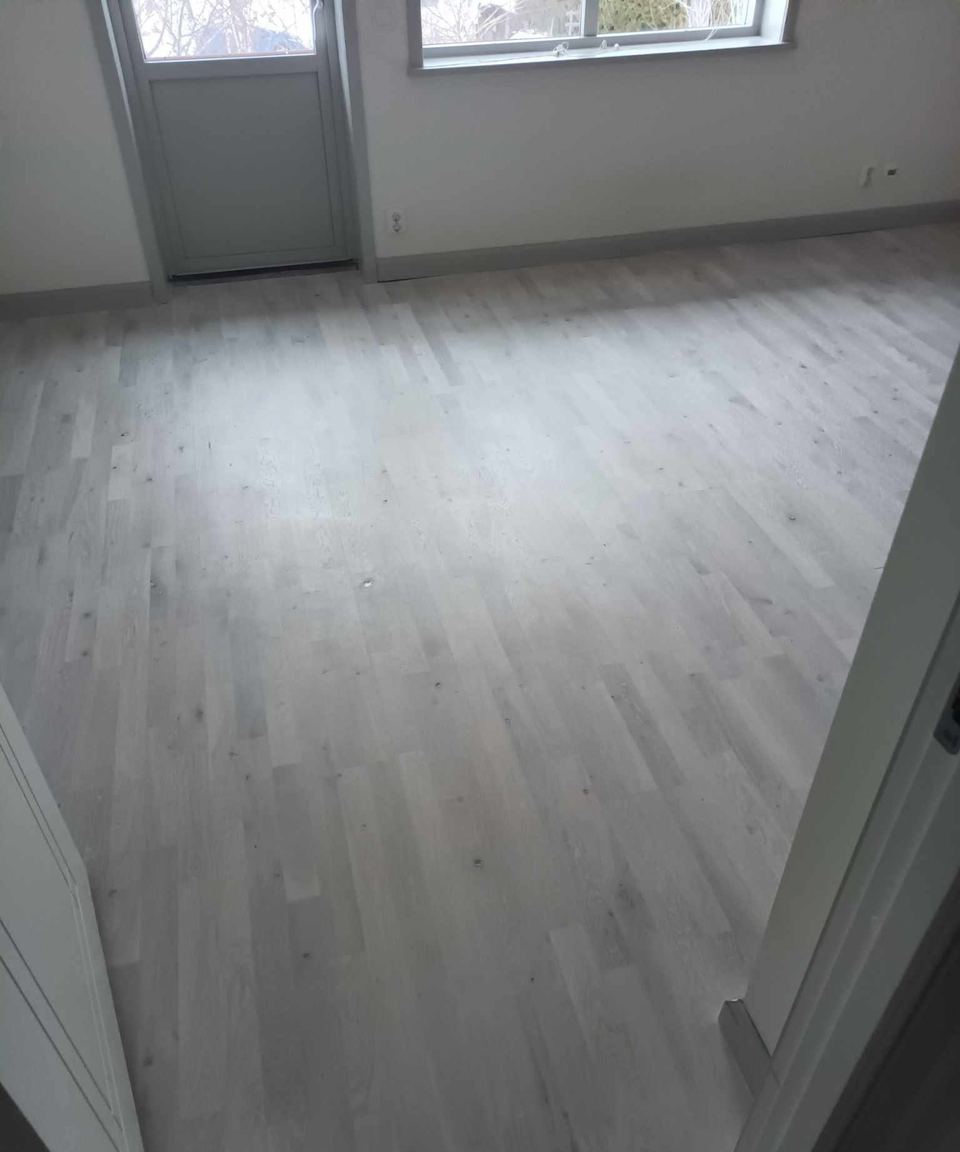 Nylagt ljust ekgolv i rum med altandörr